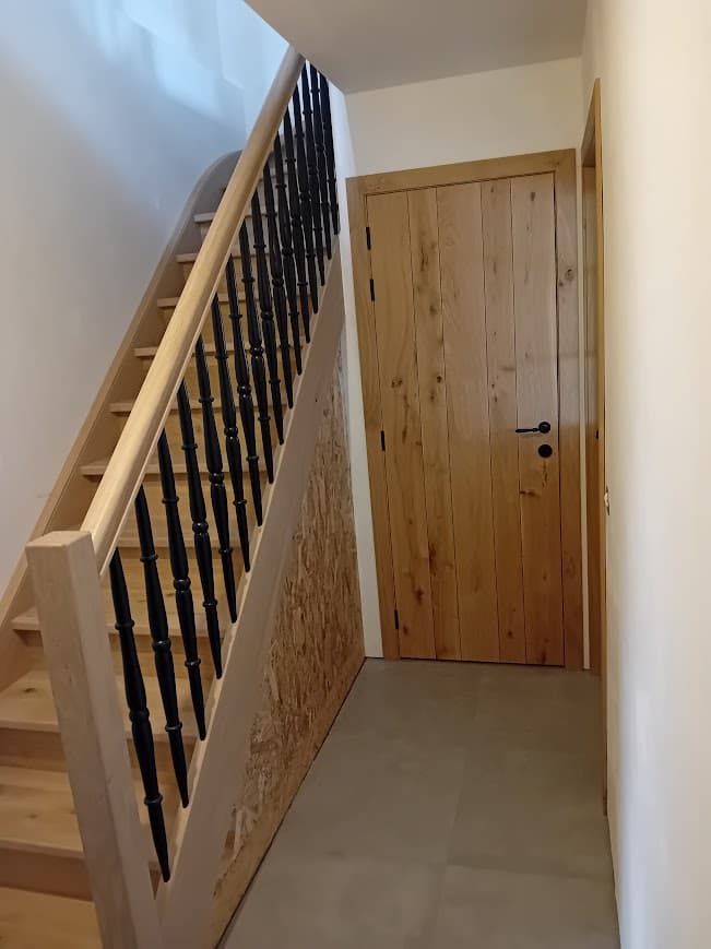 Houten trap met zwarte spijlen en eiken deur op maat